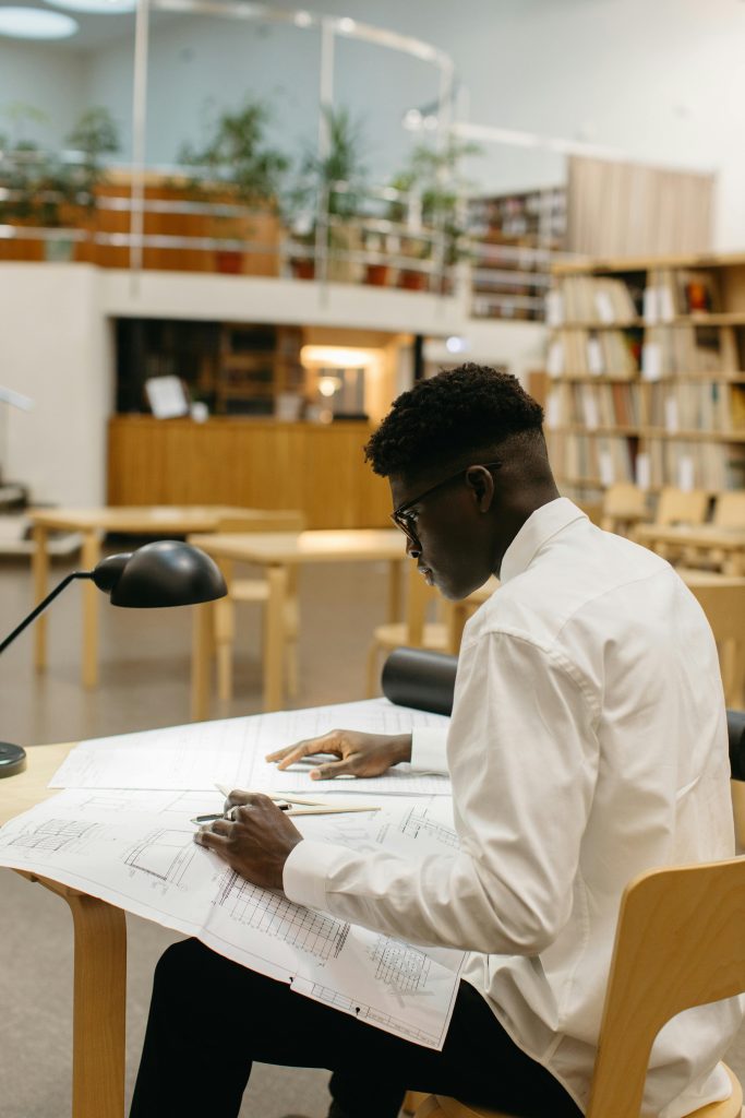 pexels-photo-6283214-6283214 Focused architect studying plans in a contemporary library setting.